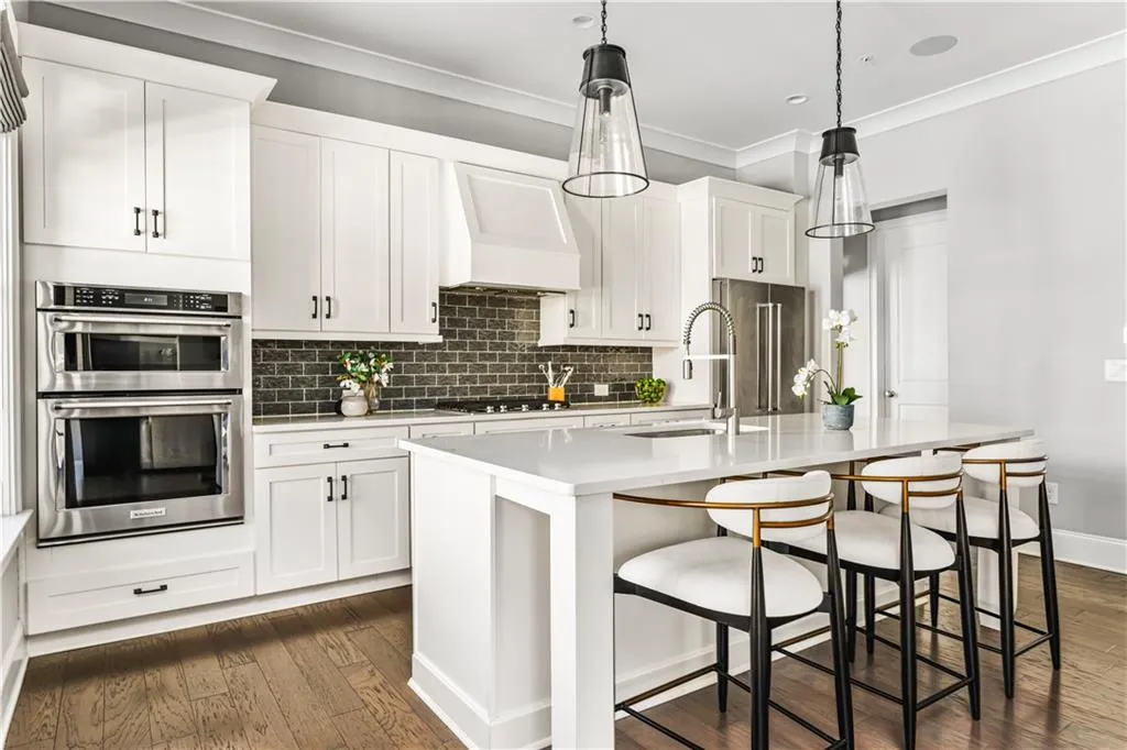 Kitchen featuring a center island with sink, custom range hood, stainless steel appliances, light countertops, and a sink