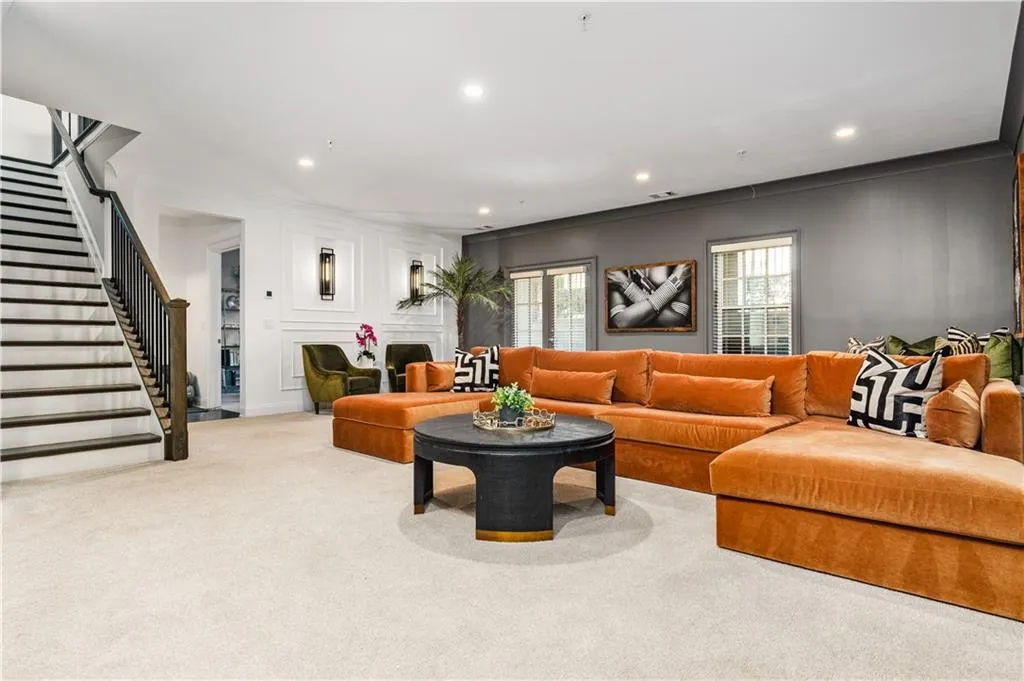 Living area with carpet floors, recessed lighting, a decorative wall, and stairway