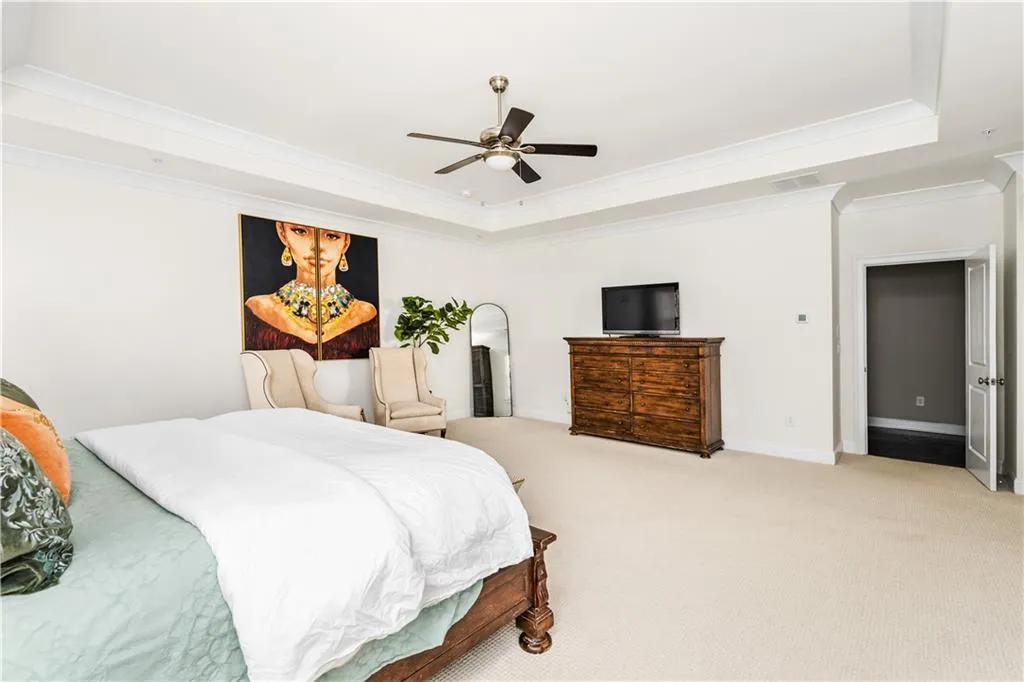Bedroom featuring ornamental molding, a tray ceiling, baseboards, and light colored carpet