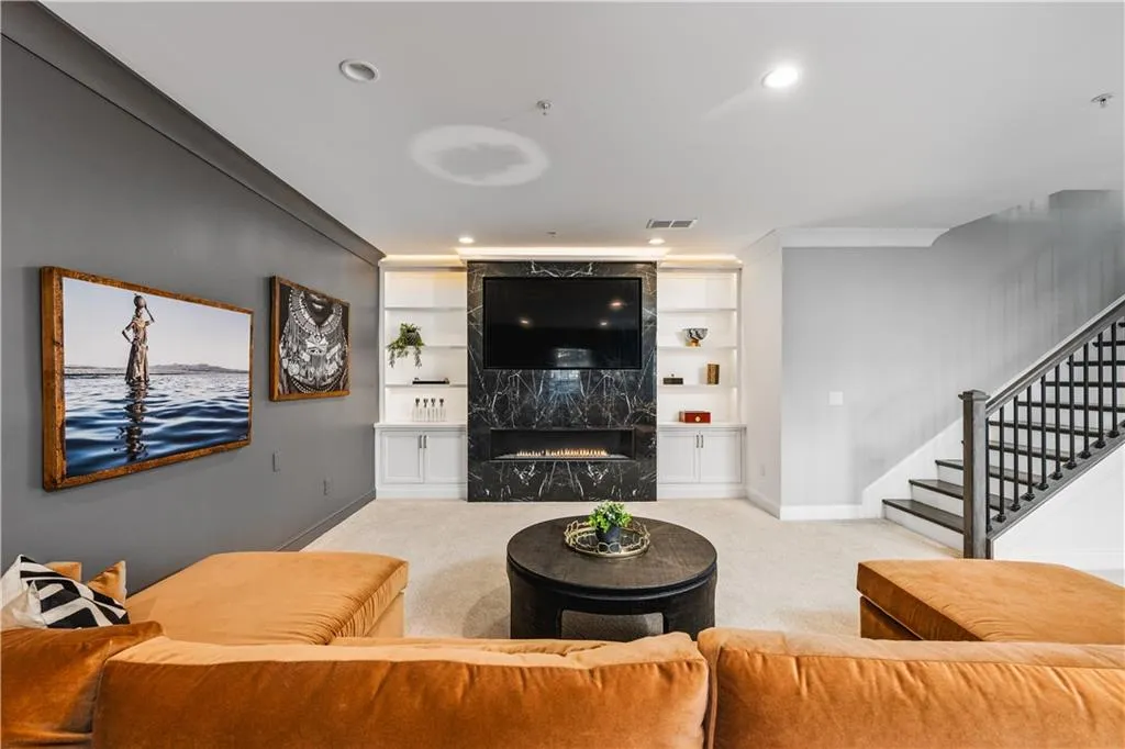 Carpeted living room with built in shelves, a high end fireplace, visible vents, stairs, and baseboards