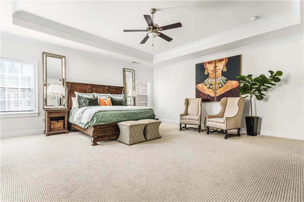 Carpeted bedroom with baseboards, a tray ceiling, a ceiling fan, and ornamental molding