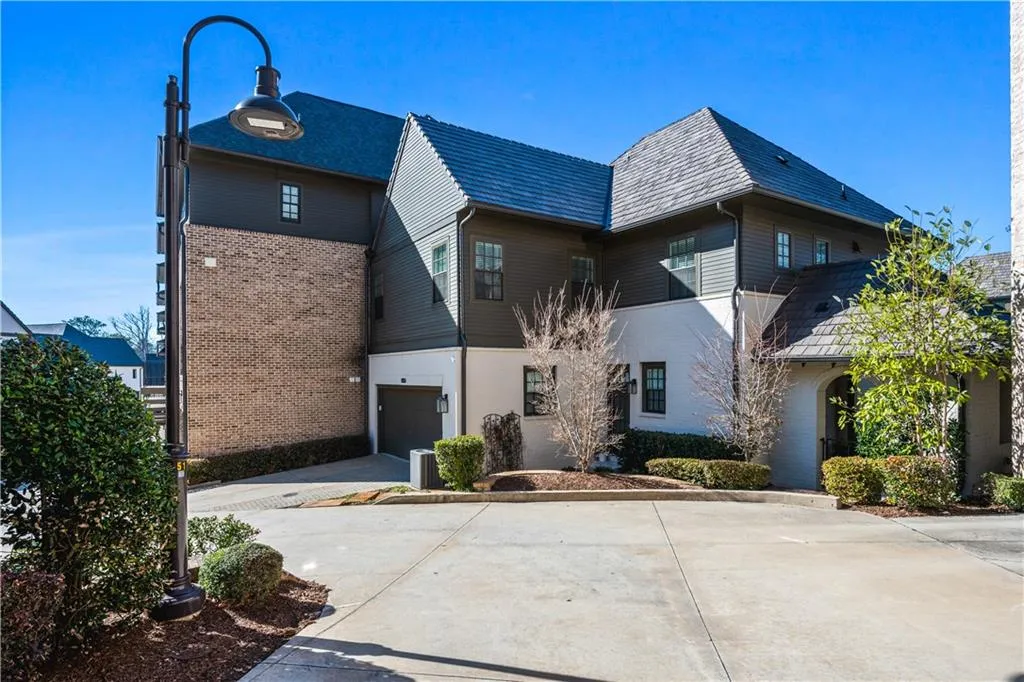 View of front facade featuring driveway, a garage, a high end roof, and brick siding