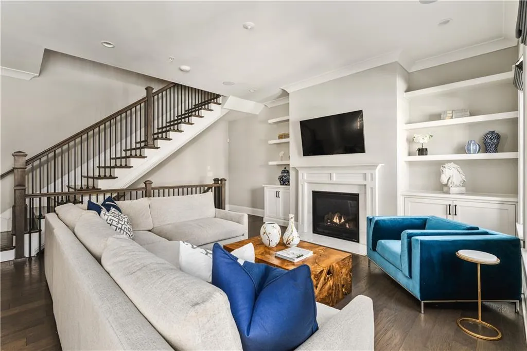 Living room featuring dark wood-style floors, ornamental molding, built in shelves, and stairs