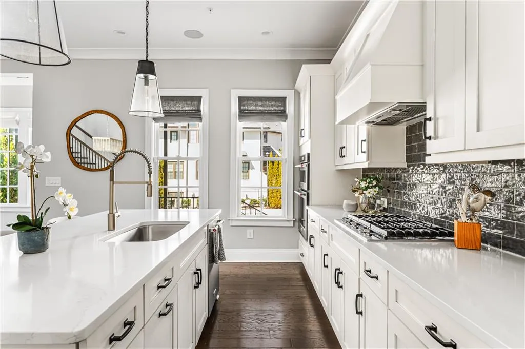 Kitchen with crown molding, custom exhaust hood, backsplash, appliances with stainless steel finishes, and a sink