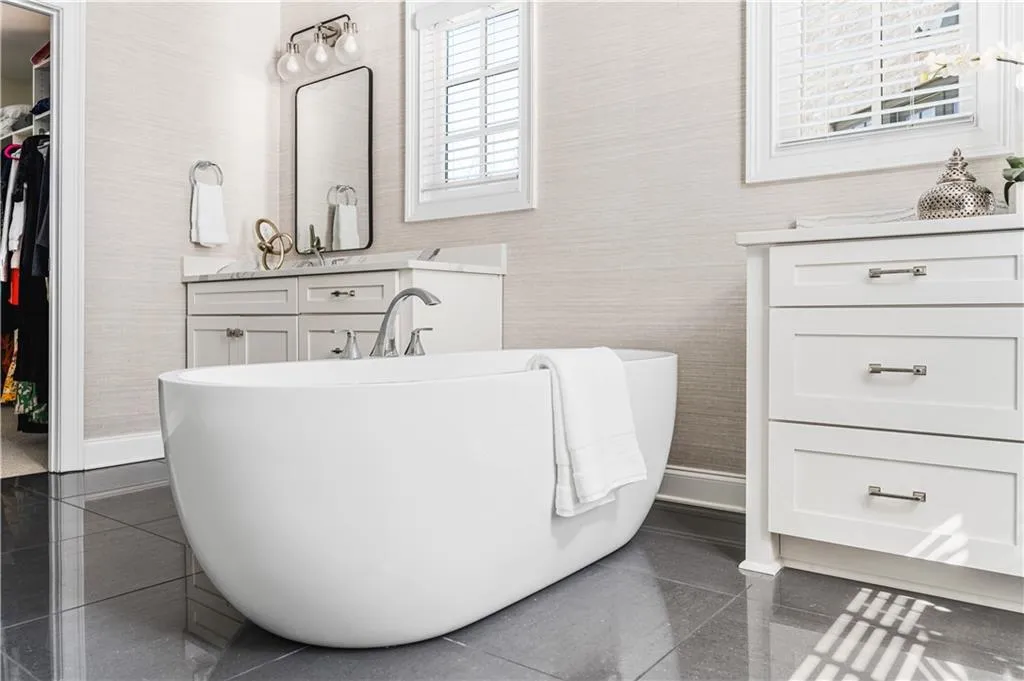 Full bathroom featuring a walk in closet, a soaking tub, granite finish floor, and vanity