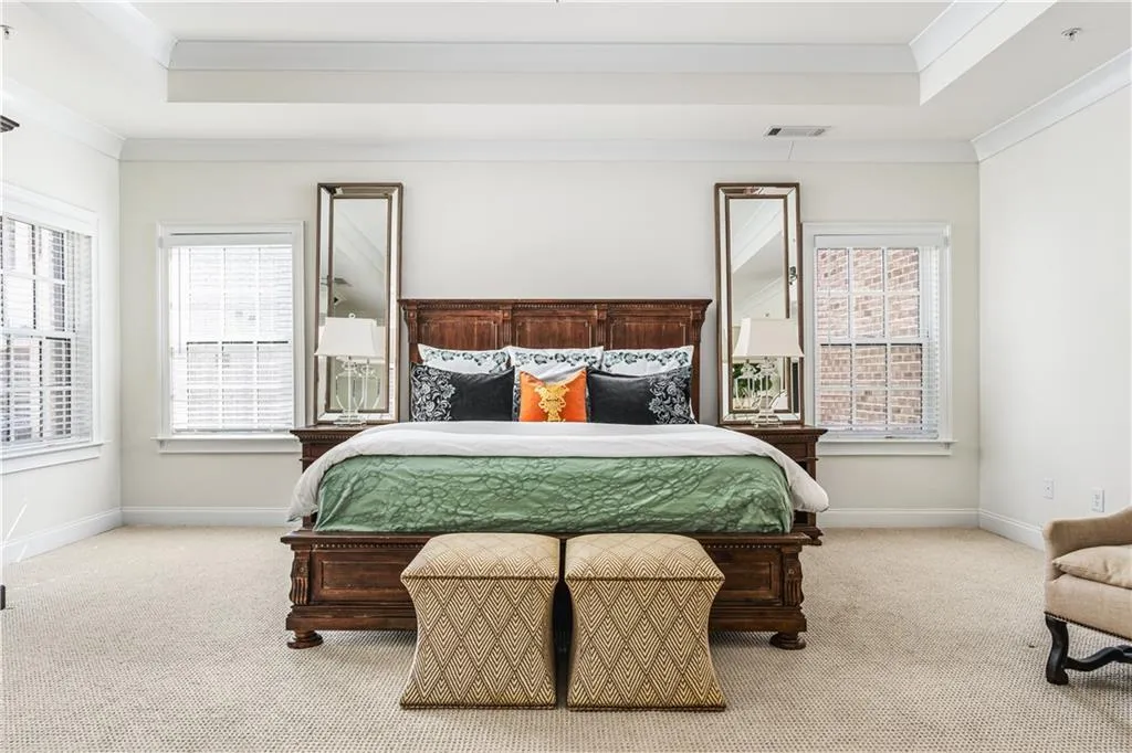 Carpeted bedroom featuring a raised ceiling, visible vents, crown molding, and baseboards
