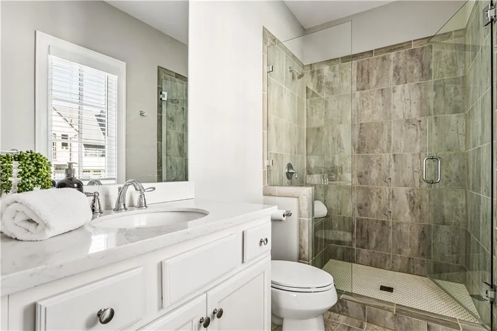 Bathroom featuring vanity, a shower stall, and toilet