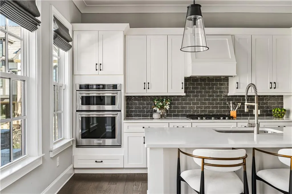 Kitchen with cooktop, a sink, stainless steel double oven, premium range hood, and a wealth of natural light