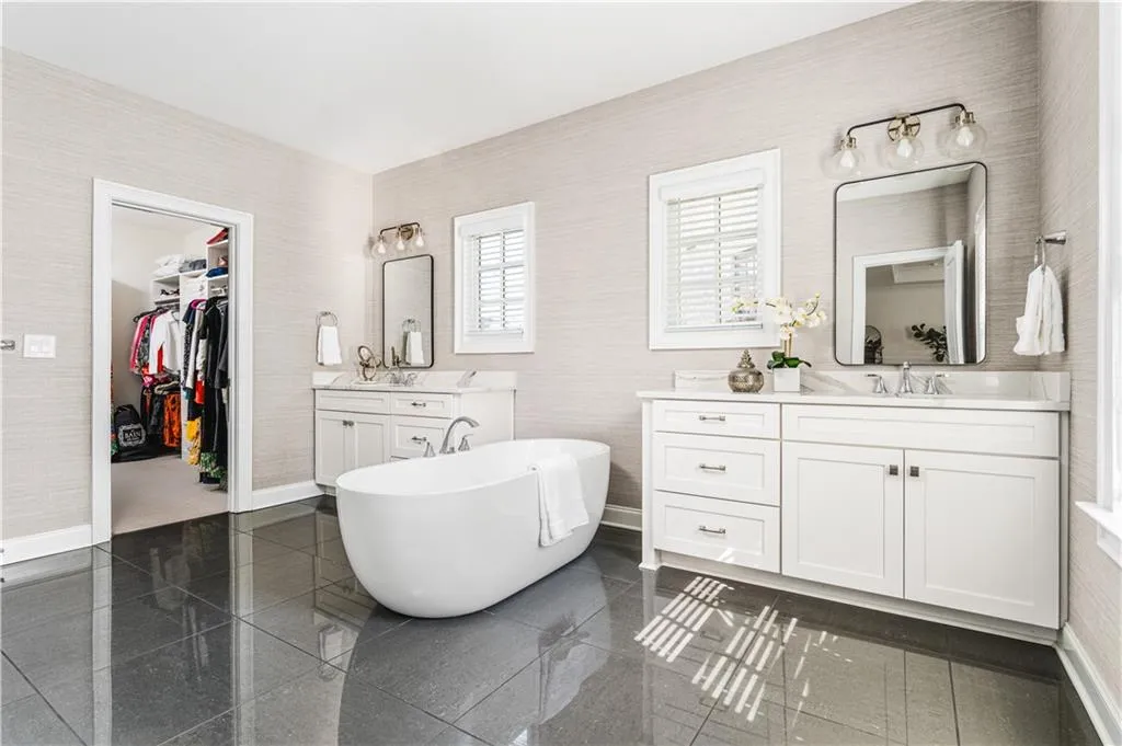Full bath featuring baseboards, a sink, a freestanding bath, granite finish floor, and two vanities