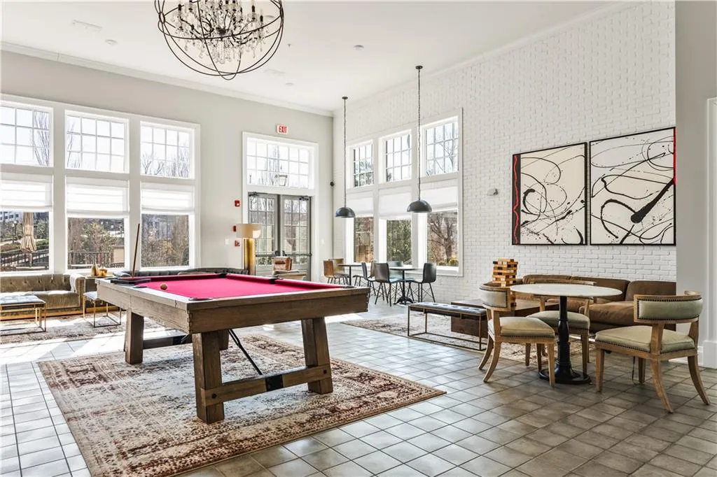 Rec room featuring billiards, brick wall, a high ceiling, crown molding, and a chandelier