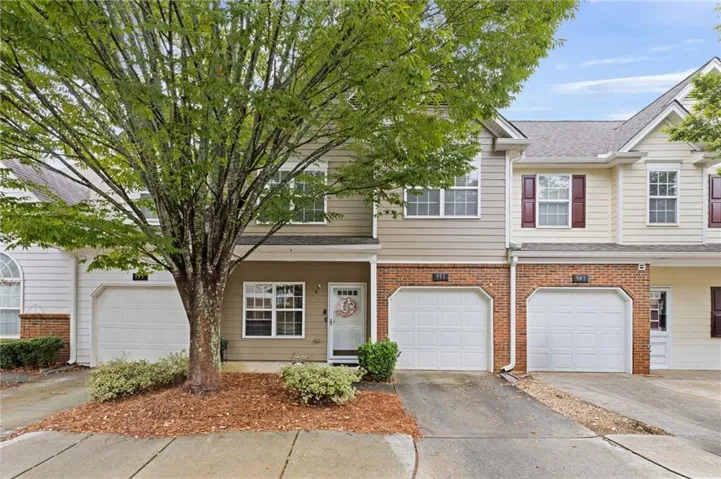 Attached garage with a paved driveway, brick facade, siding exterior, and shuttered windows