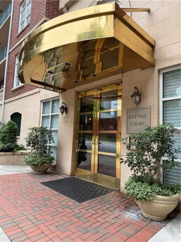 Polished brass awning and double entry doors, brick paver entryway, and decorative exterior lighting