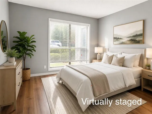 Spacious room featuring wood-finish flooring, a large window with horizontal blinds, and light gray wall paint