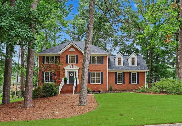 Brick exterior residence featuring a gabled roofline and dark shutters