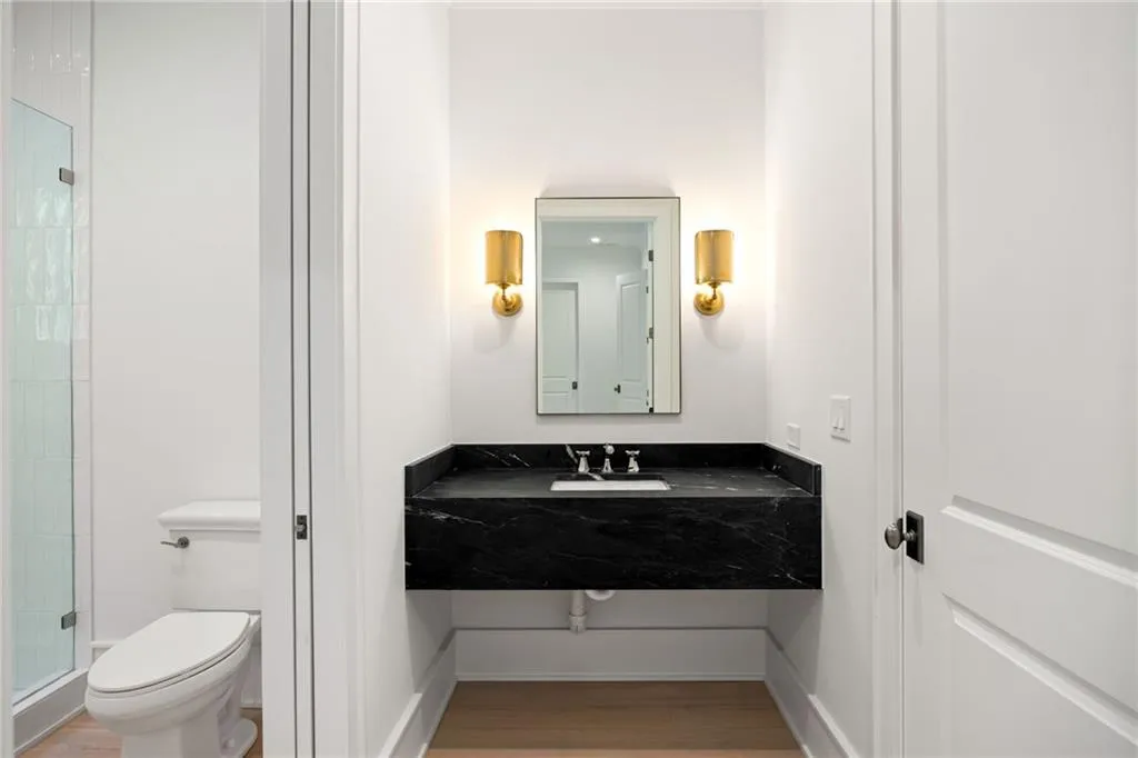 Floating vanity with a black stone countertop, undermount sink, and wall-mounted sconces