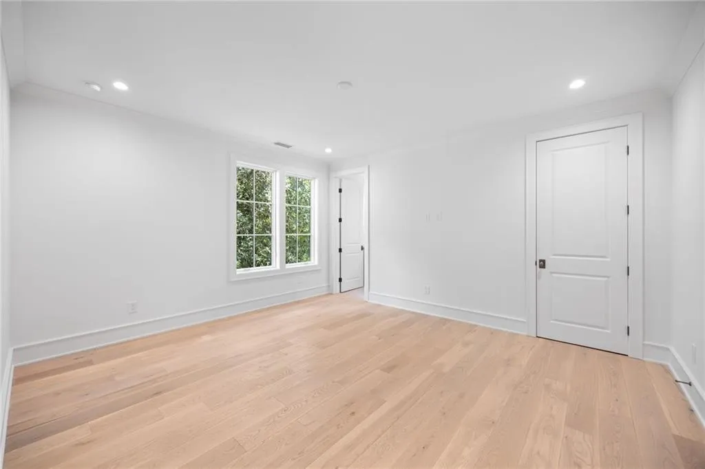 Recessed ceiling lighting, wood-finish flooring, white trim, and a window with natural light