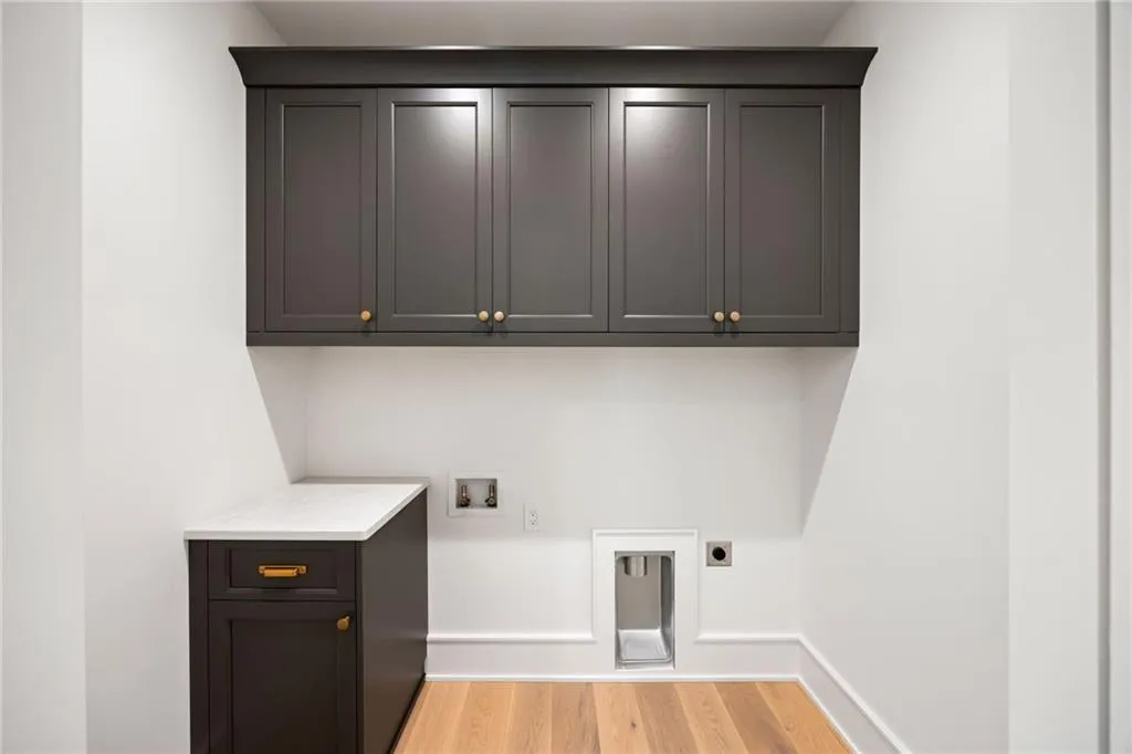 Laundry area featuring dark gray cabinetry, white countertops, wood-finish flooring, and white baseboard molding