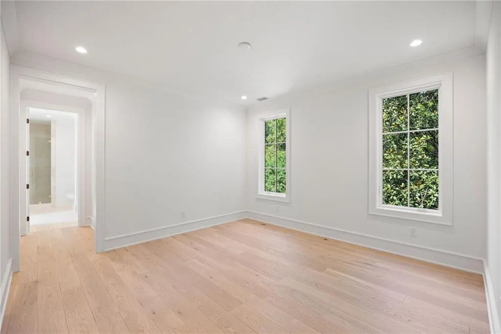 Light wood-finish flooring with recessed lighting, crown molding, and two multi-pane windows