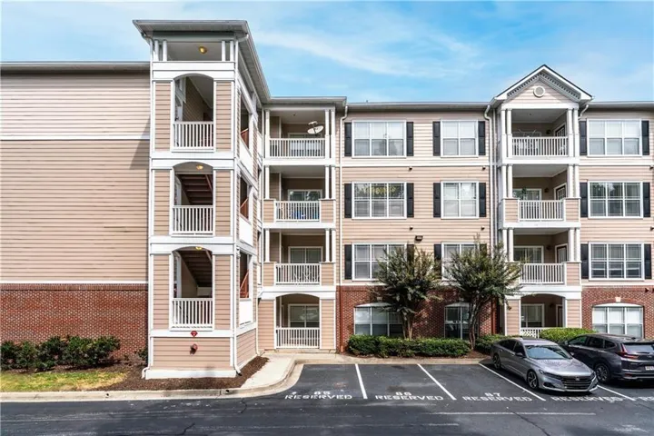 Multi-story residential building featuring private balconies, traditional shutters, brick accents, and dedicated parking spaces