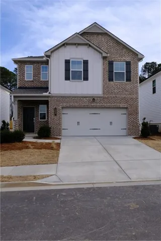 Two-story residence featuring a brick and board-and-batten facade, attached two-car garage, and a concrete driveway