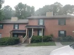View of front of home with a chimney, covered porch, and brick siding
