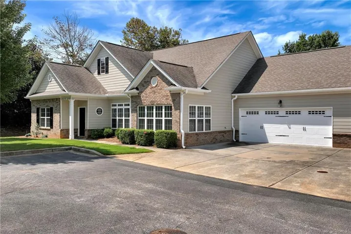 Exterior featuring brick and siding finishes, a two-car garage with decorative hardware, an asphalt driveway, and manicured landscaping