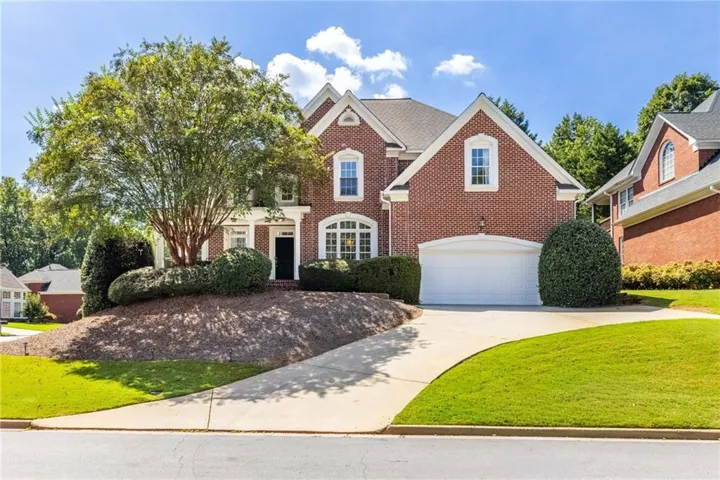 Traditional brick exterior with white trim, a multi-car driveway, and a two-car garage