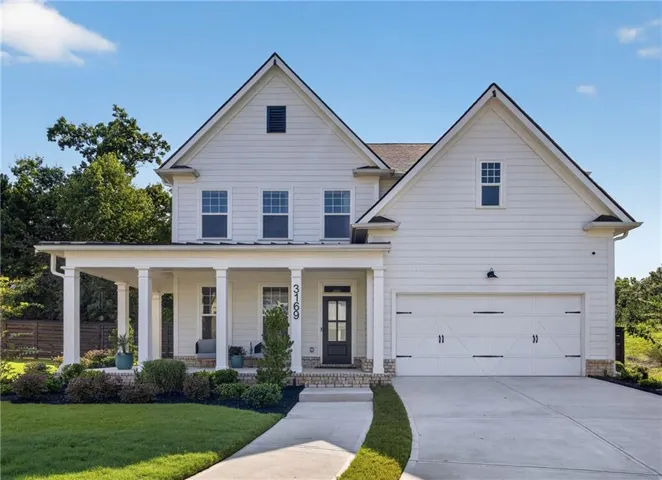 White siding exterior with a dark shingle roof and a covered front porch featuring white columns