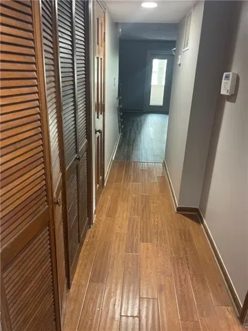Wood-finish flooring leading to a recessed panel door