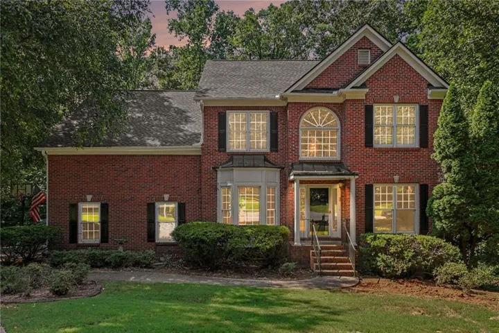 Traditional brick exterior featuring a prominent arched window, bay window, and gabled roofline
