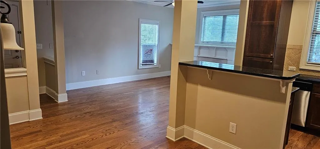 Kitchen featuring dark wood finished floors, a kitchen breakfast bar, stainless steel dishwasher, and ceiling fan