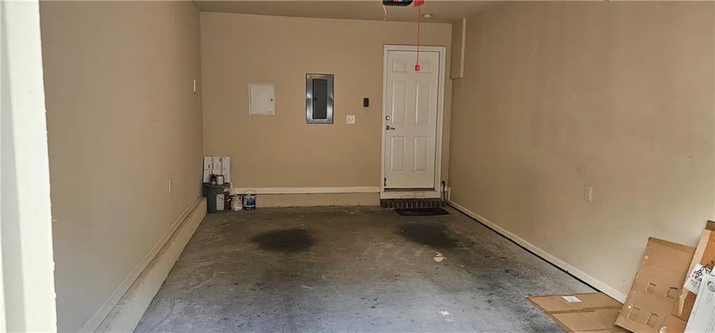Garage with door opener, baseboards and electric panel