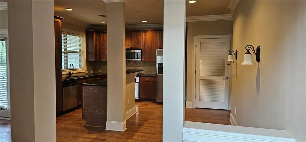 Kitchen with crown molding, backsplash, stainless steel appliances, dark wood-style floors, and recessed lighting
