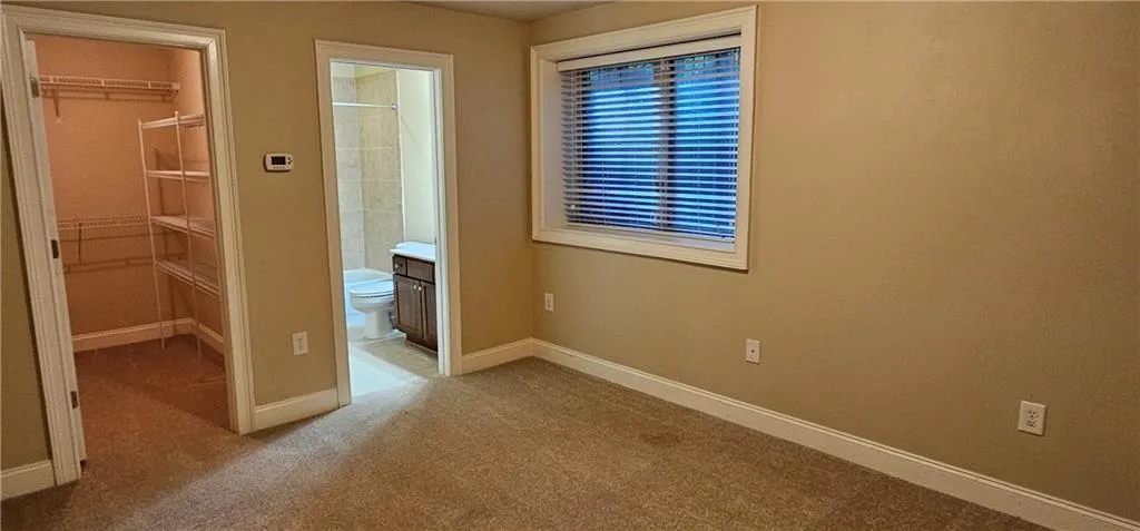 Second bedroom with carpet, a walk in closet, ensuite bathroom, and a closet