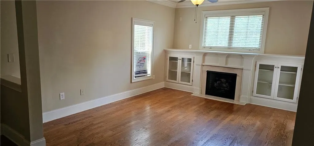 Living room with ornamental molding, plenty of natural light, a high end fireplace, and wood finished floors