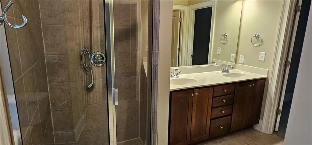 Full bath with a separate shower, double vanity, and tile patterned flooring