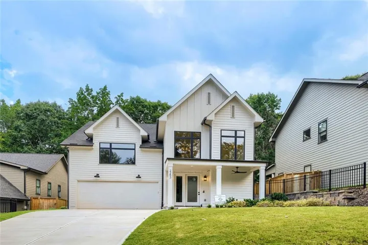 Modern farmhouse exterior with white vertical and horizontal siding, prominent gables, covered front porch, and an attached two-car garage