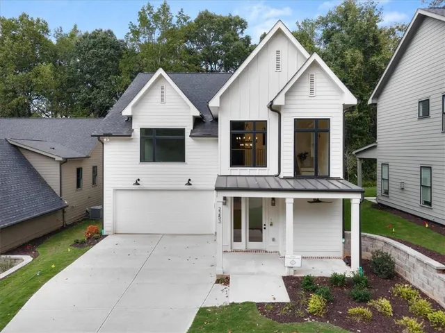 Modern farmhouse exterior with white board and batten siding, black-framed windows, and a covered front porch with a metal roof