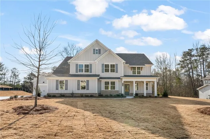 Modern farmhouse featuring board and batten siding, a porch, a front lawn, and roof with shingles