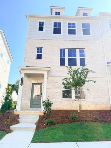 Three-story exterior featuring white brick, light blue siding, multiple windows, a covered entry, and a light green front door