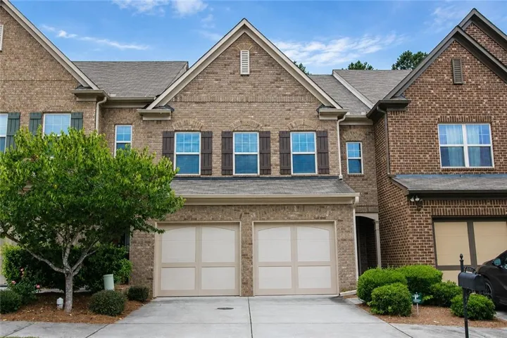 Brick exterior with multiple gables, a two-car garage, and shuttered windows