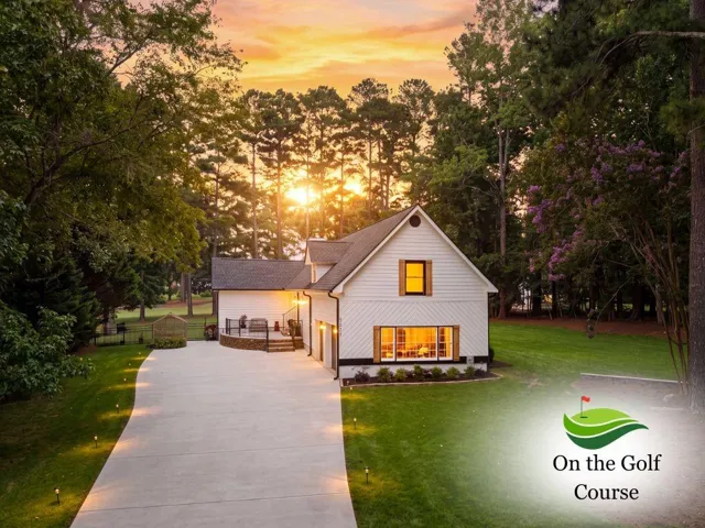 White siding with dark-trimmed windows, a stone-accented exterior, and a built-in garage