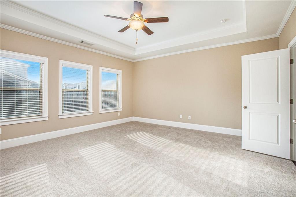 Unfurnished room with crown molding, a raised ceiling, light colored carpet, and ceiling fan