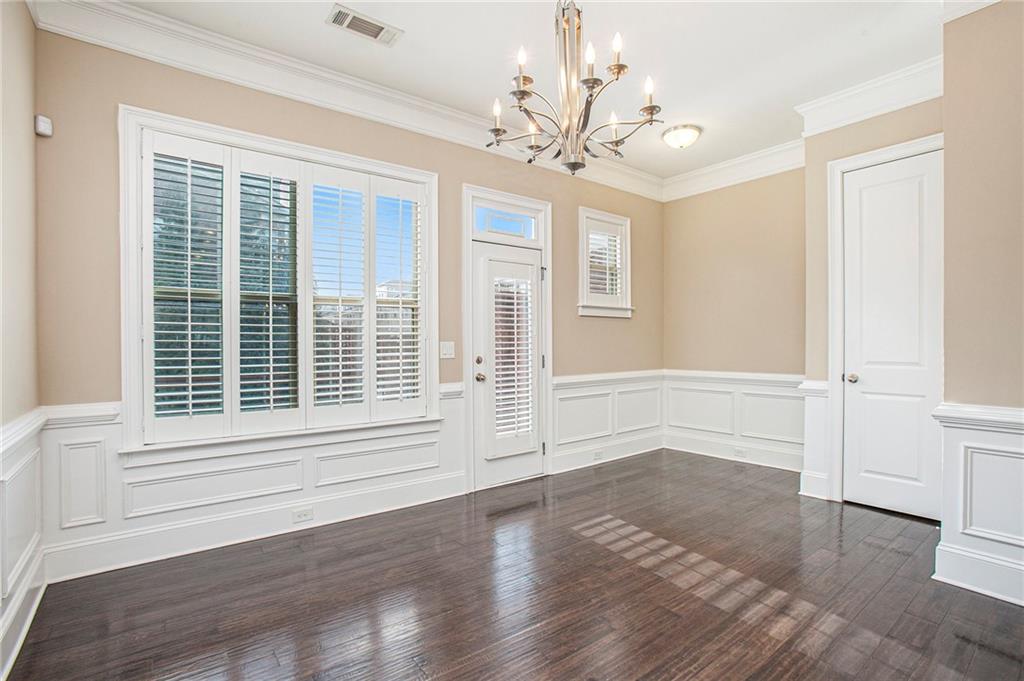 Unfurnished room with a chandelier, dark hardwood / wood-style flooring, and ornamental molding