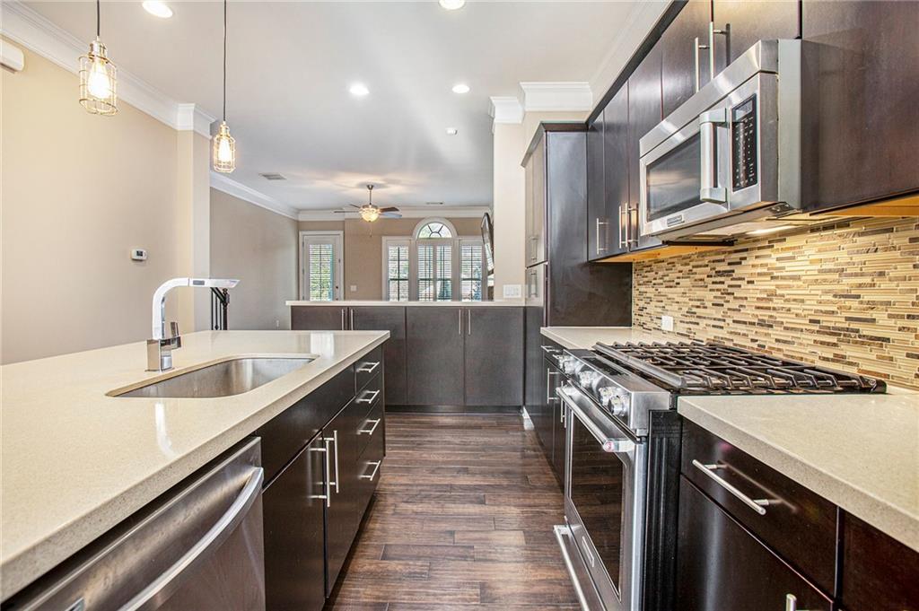 Kitchen with ceiling fan, pendant lighting, dark hardwood / wood-style flooring, appliances with stainless steel finishes, and sink