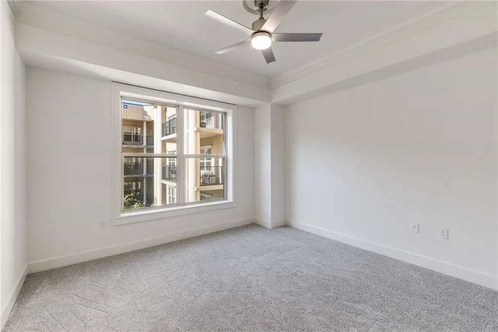 Bedroom with ceiling fan, light colored carpet, and crown molding