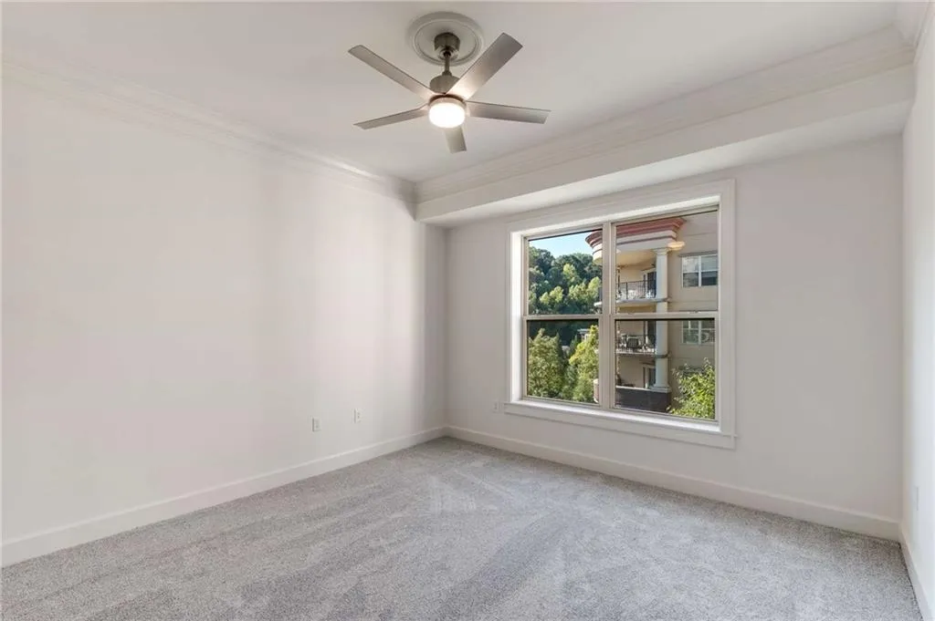 Carpeted bedroom featuring ceiling fan and ornamental molding