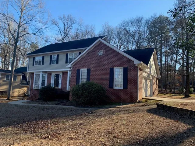 View of front of property with brick siding, driveway, and an attached garage