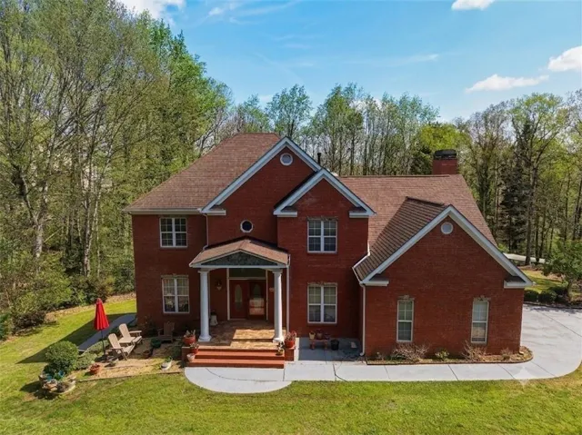 Brick facade, columned front porch, expansive front lawn, paved driveway, mature trees