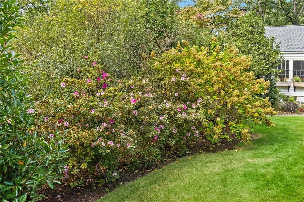 Gorgeous flowering bushes and majestic trees surround the home , creating a peaceful, park-like setting.